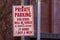 A metal sign at a parking lot that says ` Private Parking, violators will be towed at owner`s expense