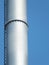 Metal silver industrial chimney against blue sky