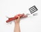 Metal spatula and fork with a wooden handle for a picnic in a female hand with painted red nails on a white background