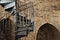 Metal spiral staircase span in retro style on the background of an old stone wall with arches