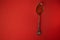 Metal spoon with elegant handle on bright red background. Red caviar of salmon species of fish in the spoon