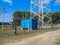 The metal structure of the cell tower behind the fence. Blue control box at the bottom