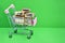 Metal supermarket trolley full of parcels in golden gift box on a rich green background