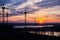 Metal tall construction crane on a background of orange sunset