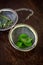 Metal tea infuser with dried leaves of green tea and fresh mint on a dark brown wooden background