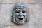 Metal theatrical mask symbolizes humor on the granite fence. Saint-Petersburg.