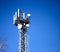 metal tower with mobile communication antennas on a blue sky background