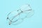 Metal transparent glasses in beautiful fashion summer concept. Glasses reading with sunlight on pastel blue background