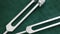Metal tuning forks on green background close up