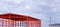 metal warehouse outline with blurred background of crane and construction workers working on rooftop of industrial building