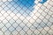 Metal wire-mesh rabitz on a blue cloudy sky background