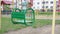Metal wooden green swing sways on chains against playground