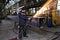 Metal worker grinds weld steel sections using an angle grinder.