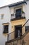 Metal wrought-iron balcony with flowers, windows and an icon on the white wall. Traditional spanish house in the city of Ronda,