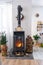 Metall black stove, burning hearth fireplace in white Festive interior of house is decorated for Christmas and New Year, Christmas