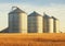 Metallic agricultural grain silos in the field.