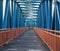 Metallic blue pedestrian bridge construction with orange railing and wooden coating close-up