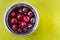 Metallic bowl full of large berries over yellow background