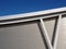 Metallic cladding on modern industrial building with steel girders and curved roof beam against a blue sky