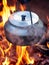 Metallic coffee pot in campfire heat