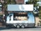 Metallic food trailer on cityscape background with blank billboard. 3d rendering