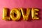 Metallic gold love text balloon on pink background with copy space