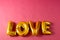 Metallic gold love text balloon on pink background with copy space