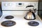 Metallic kettle on a kitchen stove with reflection