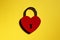Metallic red heart shaped lock on a yellow background