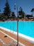 metallic shower falling drops of water and behind a swimming pool of a touristic place full of clear and transparent water with