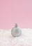 Metallic silver shiny bauble on a snow.Soft pink background.Christmas aesthetic design