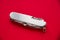 Metallic swiss knife isolated on red