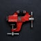 Metalwork tool - red vintage mechanical hand vise clamp on grey background. With copy space