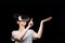 Metaverse. Portrait of woman in VR glasses point with finger at space. Black background. Concept of 3D simulation