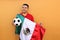 Mexican adult man plays with a soccer ball very excited that he is going to see the game with de mexican flag and wants to see his