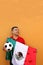 Mexican adult man plays with a soccer ball very excited that he is going to see the game with de mexican flag and wants to see his