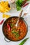 Mexican and American food Chili con carne served with nachos, pepper and herbs.