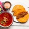 Mexican birria consomme and beef tacos on white background