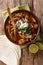 Mexican Birria de Res served with lime and tortilla closeup in a bowl. Vertical top view