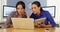 Mexican businesswomen at office desk using laptop on pad