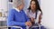 Mexican caregiver talking to elderly patient with tablet