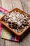 Mexican chilaquiles with mole sauce and fresh cheese on wooden background