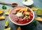 Mexican Chilli bean soup with yogurt, cheese, lime and tortilla chips in white bowl