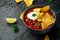 Mexican Chilli bean soup with yogurt, cheese and tortilla chips in black bowl