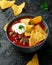 Mexican Chilli bean soup with yogurt, cheese and tortilla chips in black bowl