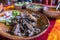 Mexican chopped lamb meat, hot sauces, and lime slices on colorful tablecloth