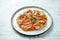 Mexican cuisine dish - tostada with salmon, sweet and sour sauce, onions, cilantro, served in a white plate on a marble background