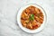 Mexican cuisine dish - tostada with salmon, sweet and sour sauce, onions, cilantro, served in a white plate on a marble background