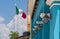 Mexican flag with colonial blue building and traditional lamps