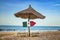 Mexican flag on wooden arrow sign. There are two sun loungers and a sun umbrella on the beach. It is a tropical paradise with a